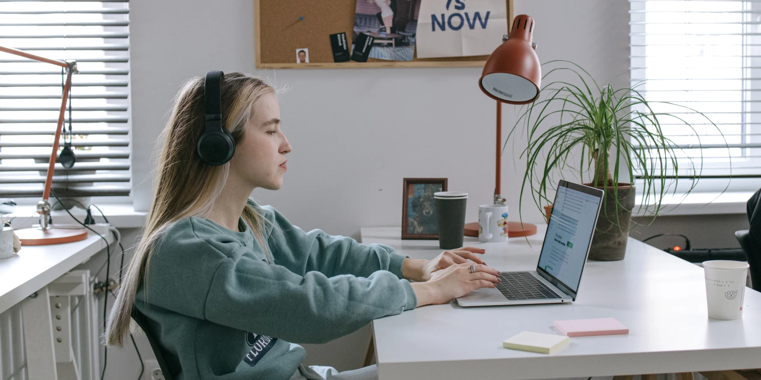 Une jeune femme concentrée devant son ordinateur portable, travaillant intensément dans un bureau lumineux, incarnation de la productivité sous pression.